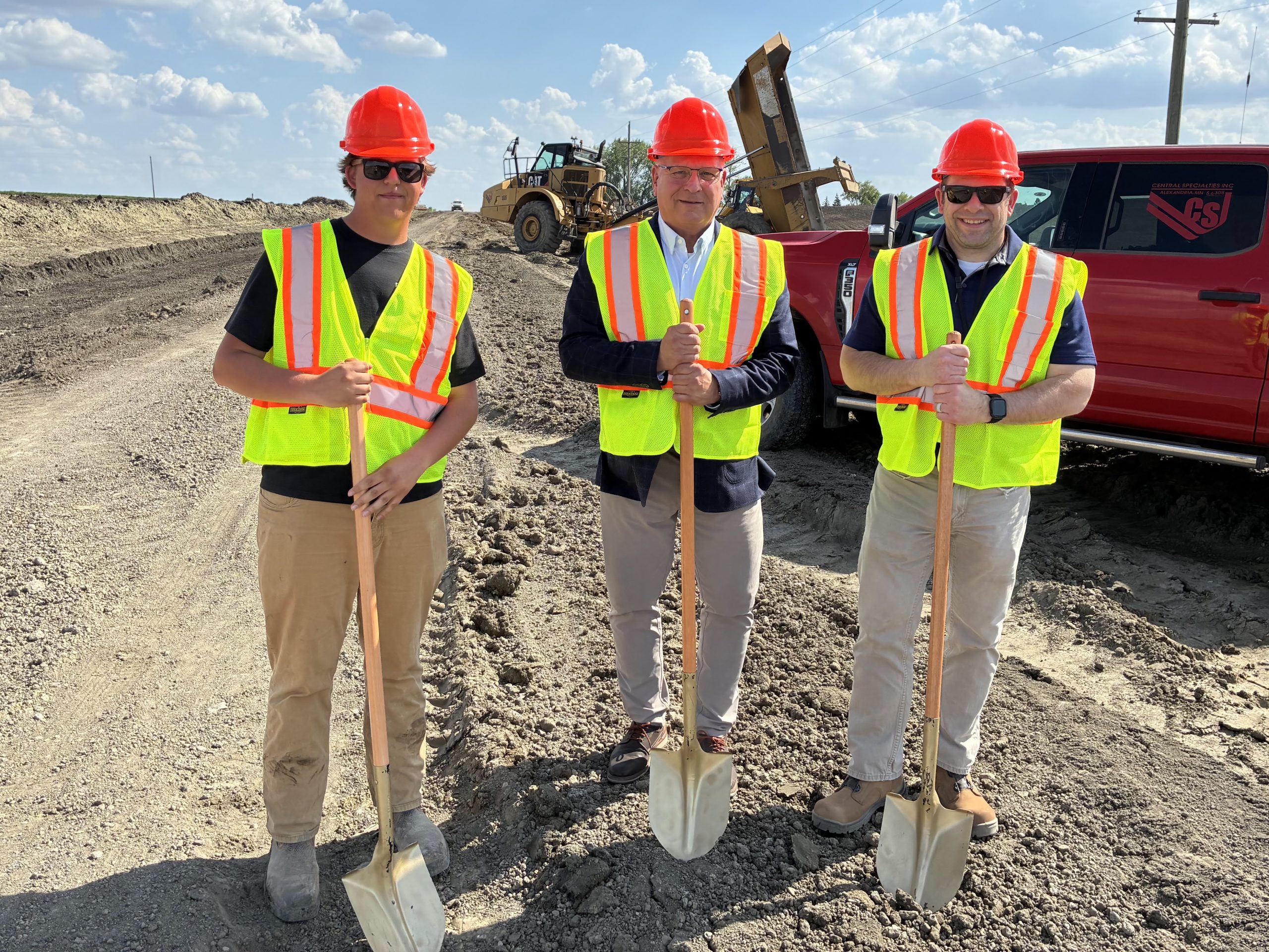 Three men with shovels at a road construction site