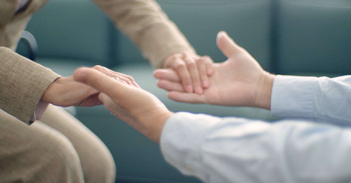 Close-up of two people holding hands, symbolizing support and compassion in a peaceful setting.