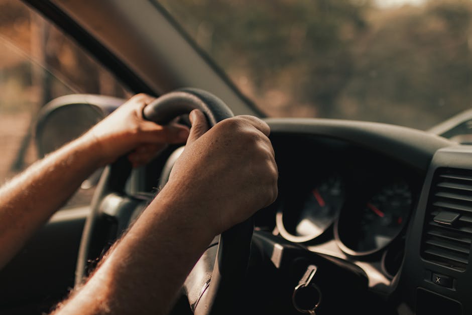 Driver's hands on a steering wheel inside a vehicle, focusing on the act of driving.
