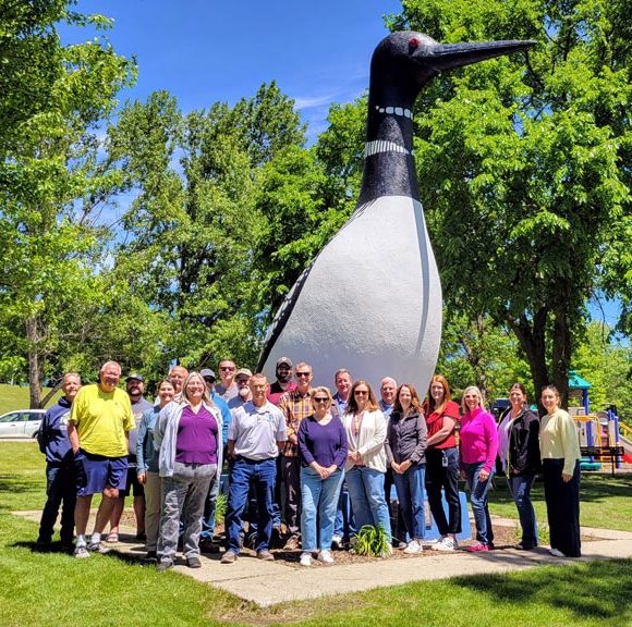 A group of people posing in front of the Vergas loon sculpture