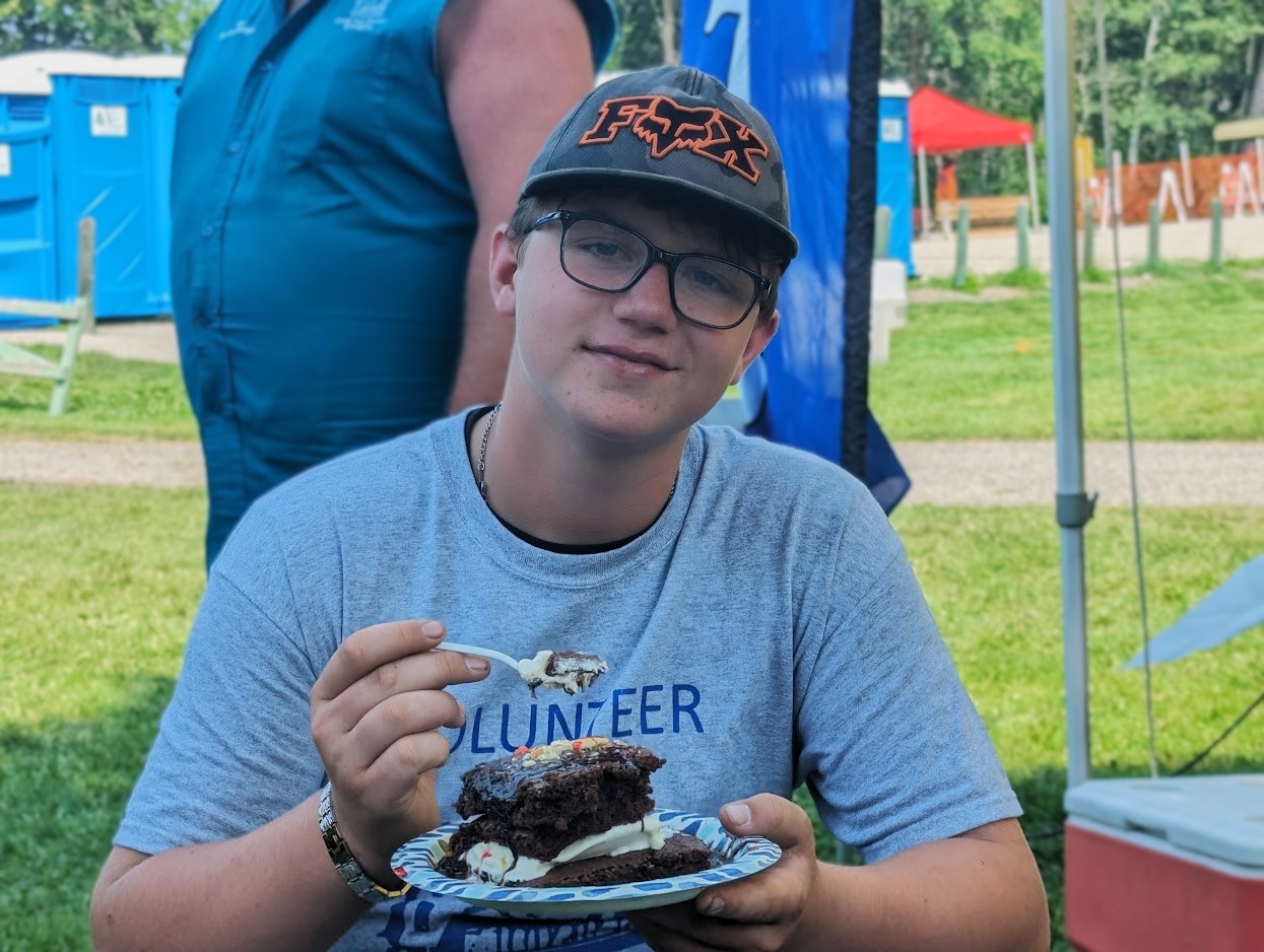 A young man eating a brownie ice cream sandwich at the Phelps Mill Festival