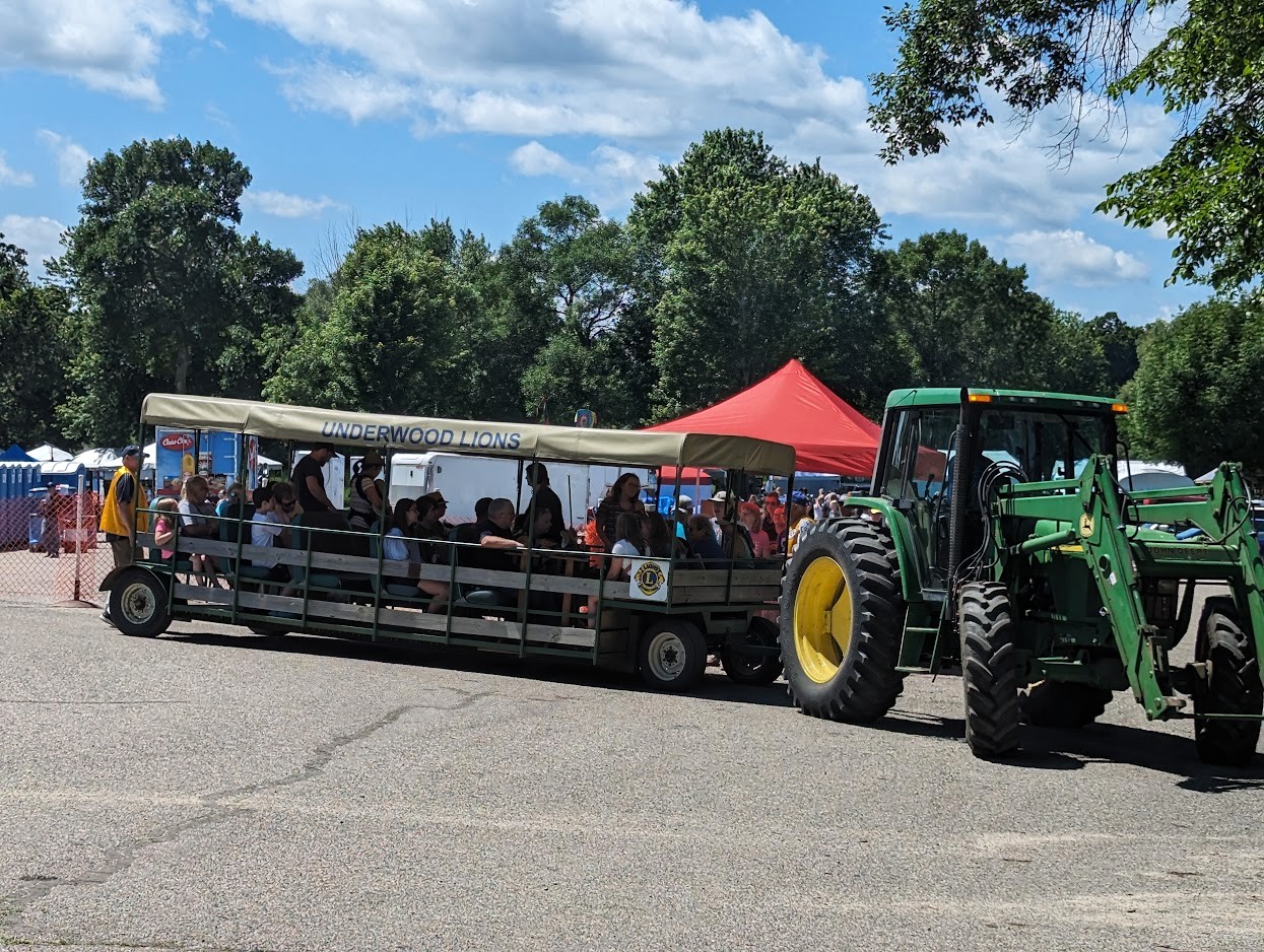 A tractor pulling a trailer full of people at the Phelps Mill Festival