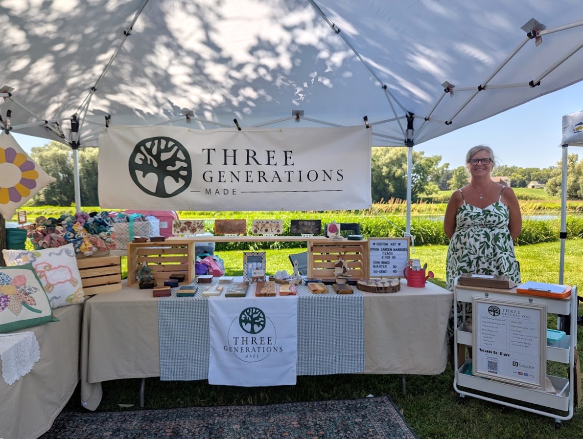 A vendor at the Phelps Mill Festival poses alongside her booth